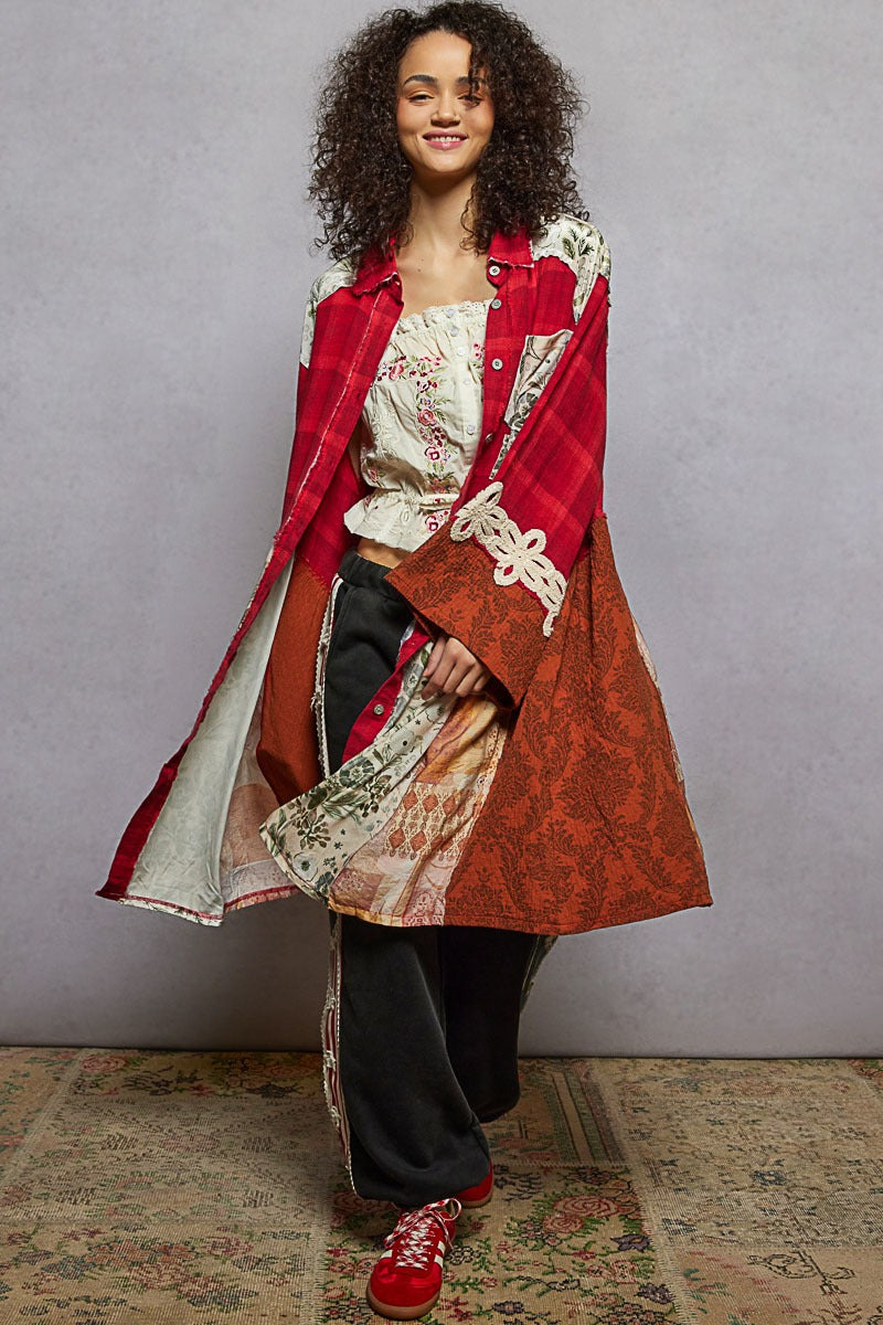 Woman wearing a long, patterned coat over a floral dress with a plain background