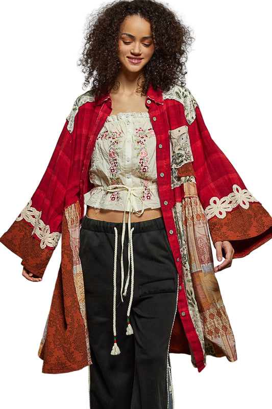 Woman wearing a red and patterned long coat over a white embroidered top and black pants on a white background