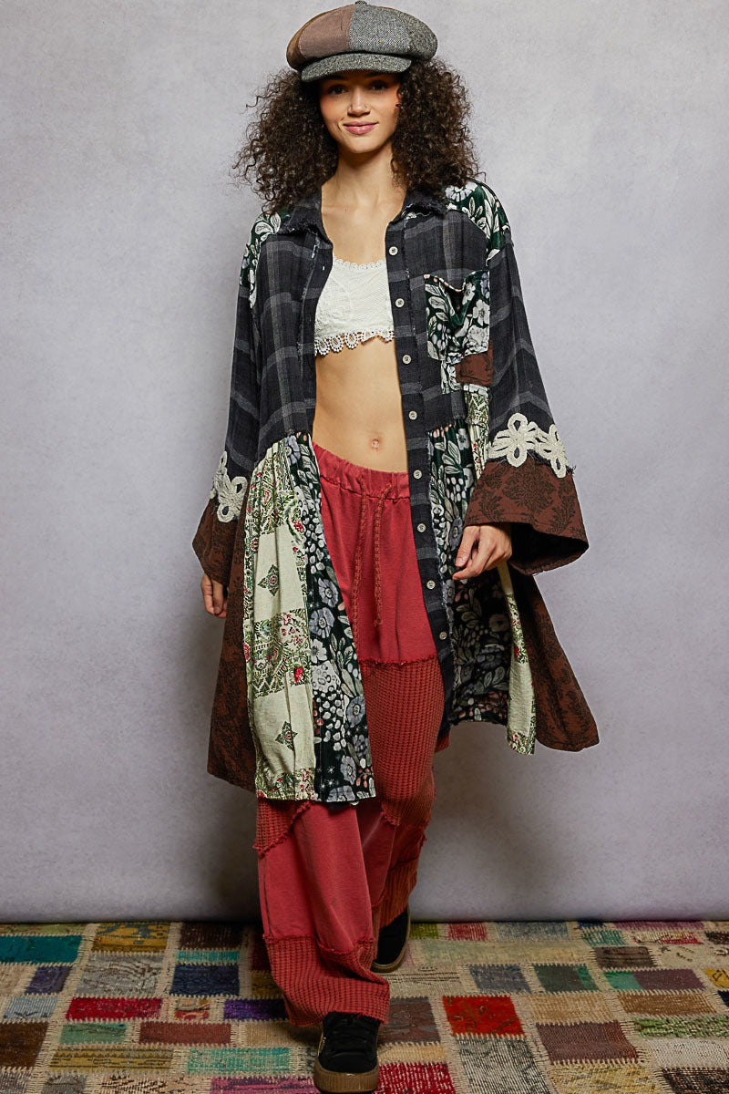 Person wearing a patchwork outfit with a plaid shirt, floral jacket, and red pants against a plain background.