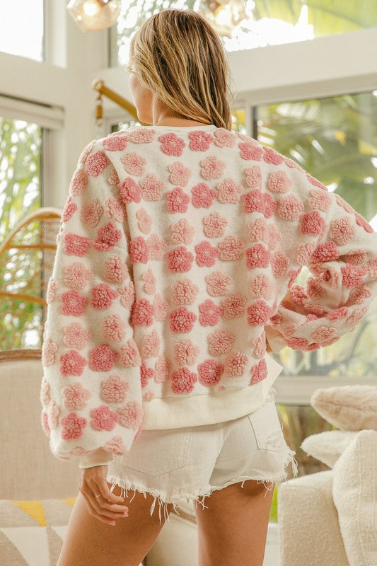 a woman standing in a living room wearing a pink and white sweater