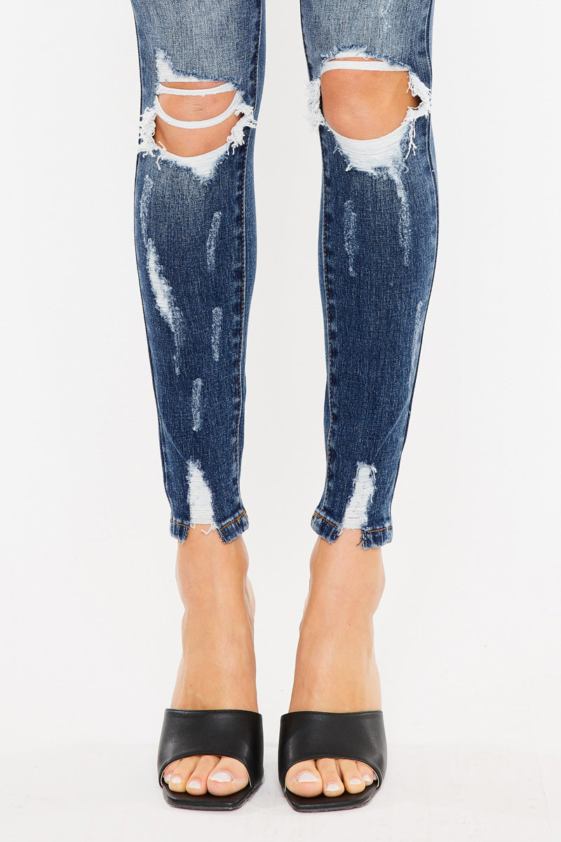 KanCan dark wash skinny jeans lower-leg close-up showing open knee rips and distressed stitched ankle hems