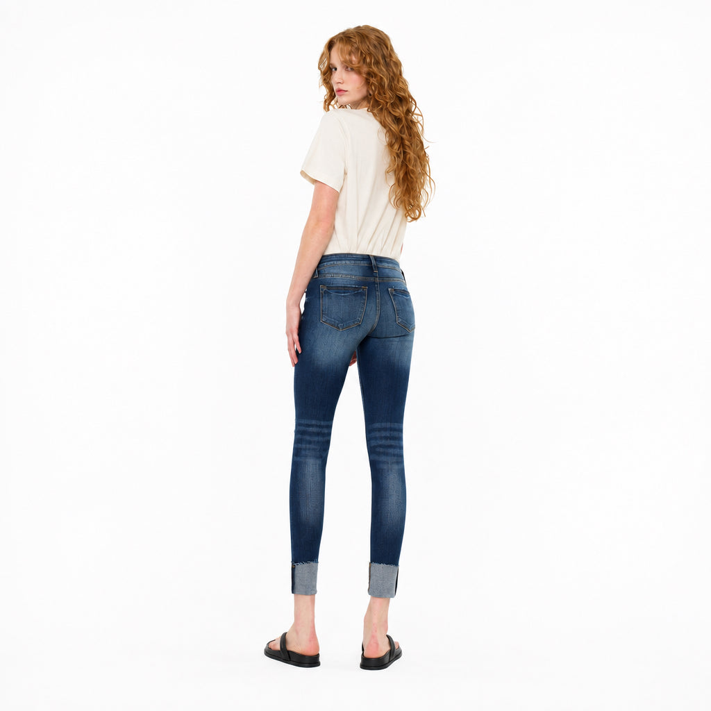 KanCan women's dark wash low-rise skinny jeans, rear three-quarter view showing back pockets and folded cuffs