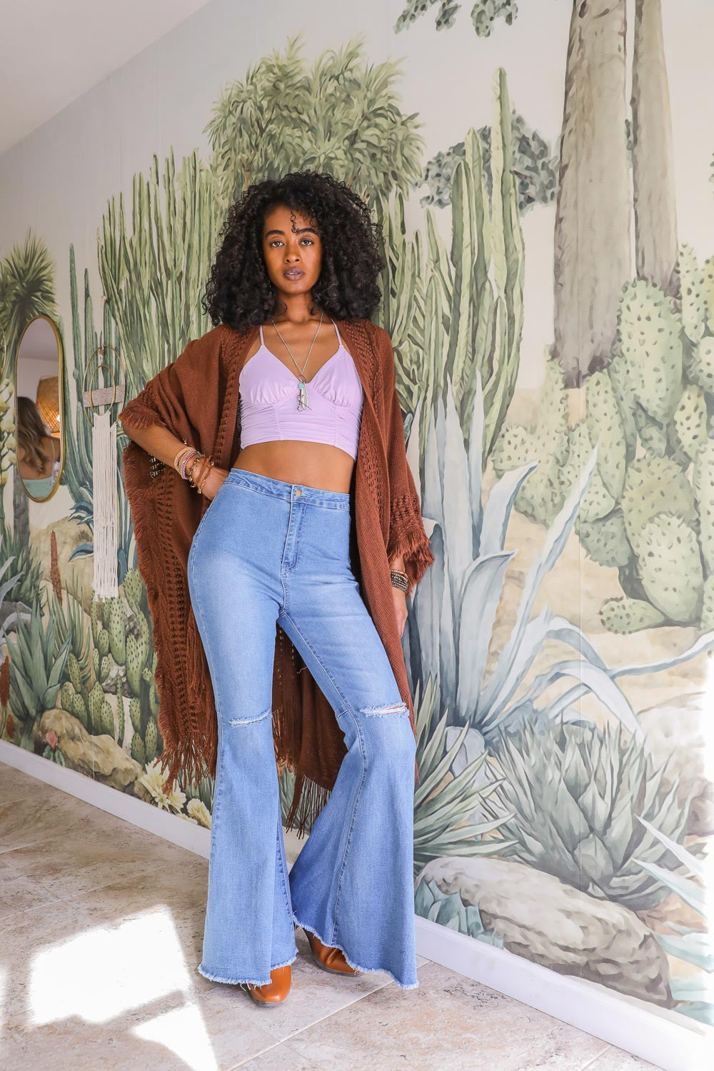 Leto Collection women's brown fringed ruana worn open over a lilac top and flared jeans