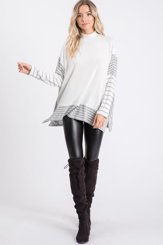 a woman wearing a white sweater and black leather pants