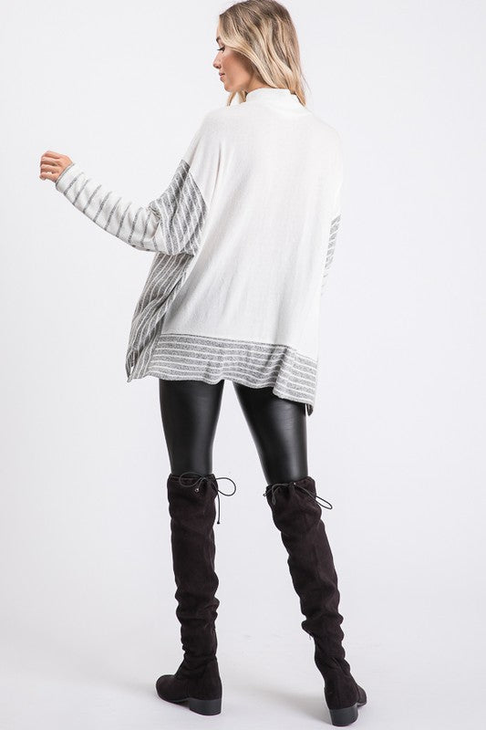 a woman wearing a white sweater and black leather pants