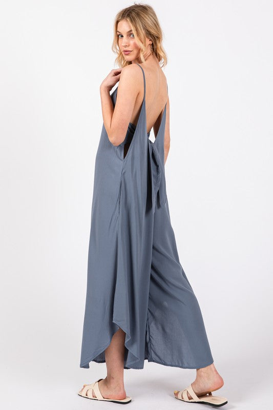 a woman in a blue dress is standing with her back to the camera