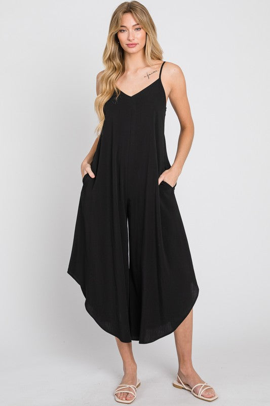 a woman wearing a black jumpsuit and sandals
