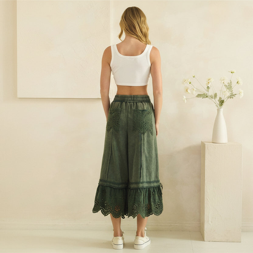 Oli & Hali teal green wide-leg pants on model, back view showing eyelet patch pockets and ruffle hem
