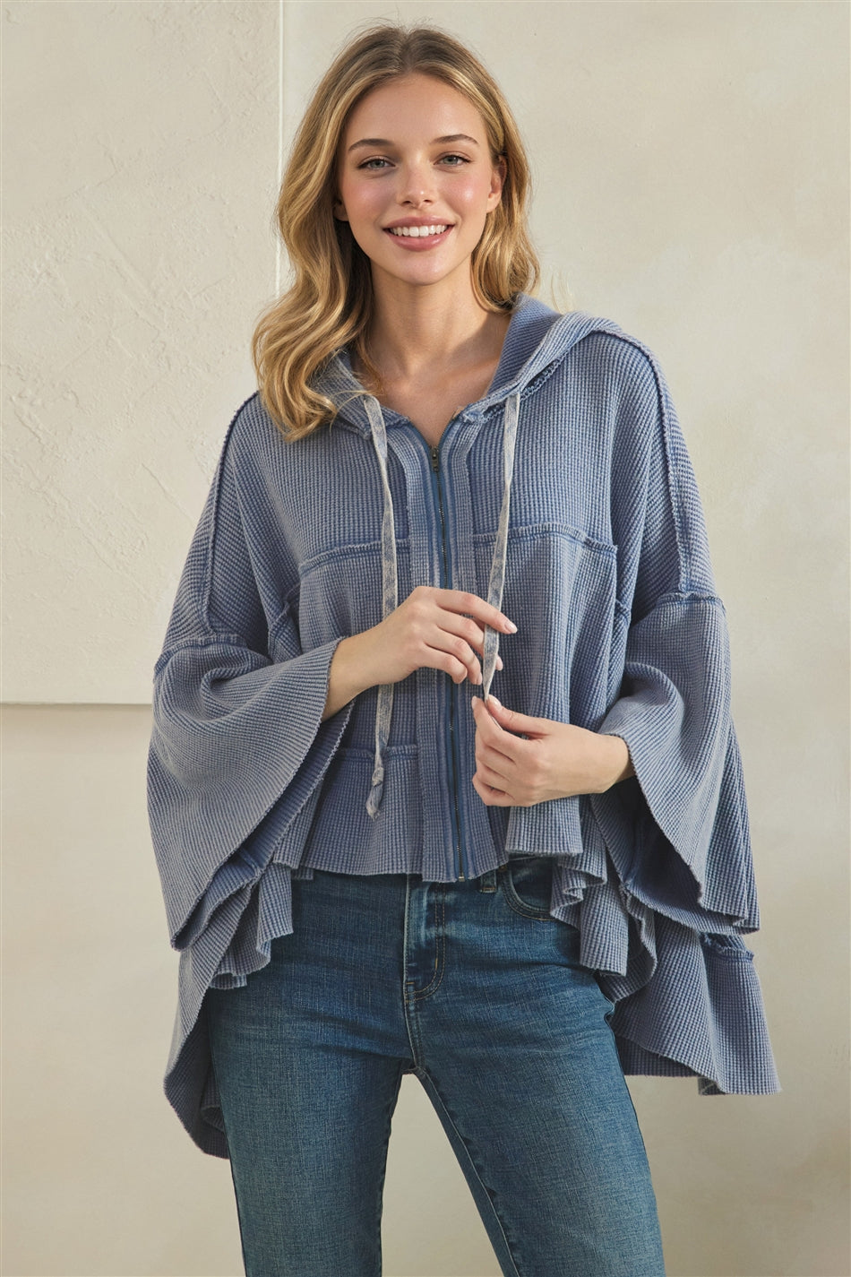 Front view of a light blue waffle hoodie with drawstrings, center zipper and flowing wide sleeves