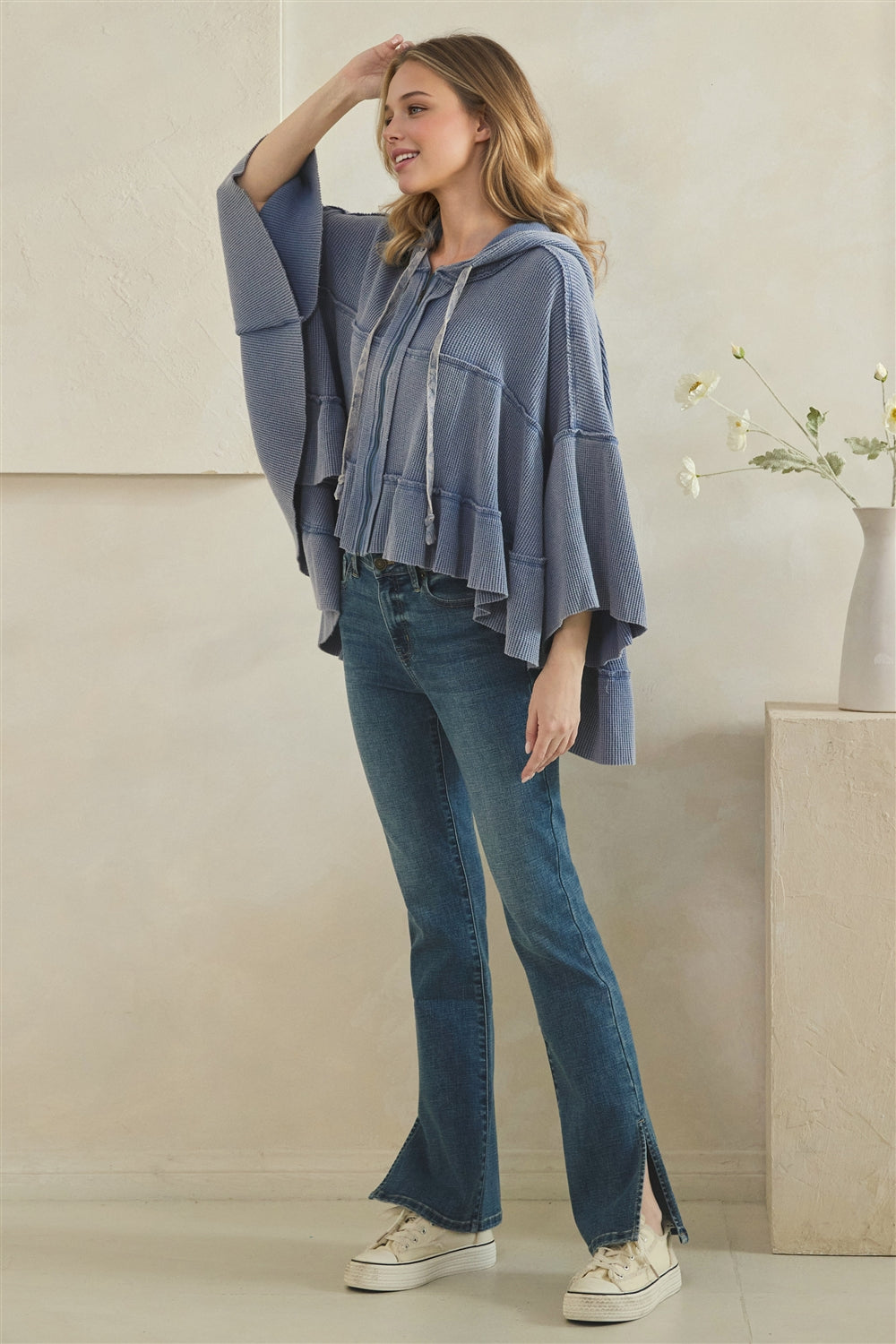 Three-quarter view of a light blue waffle zip hoodie showing the wide sleeves and longer back hem