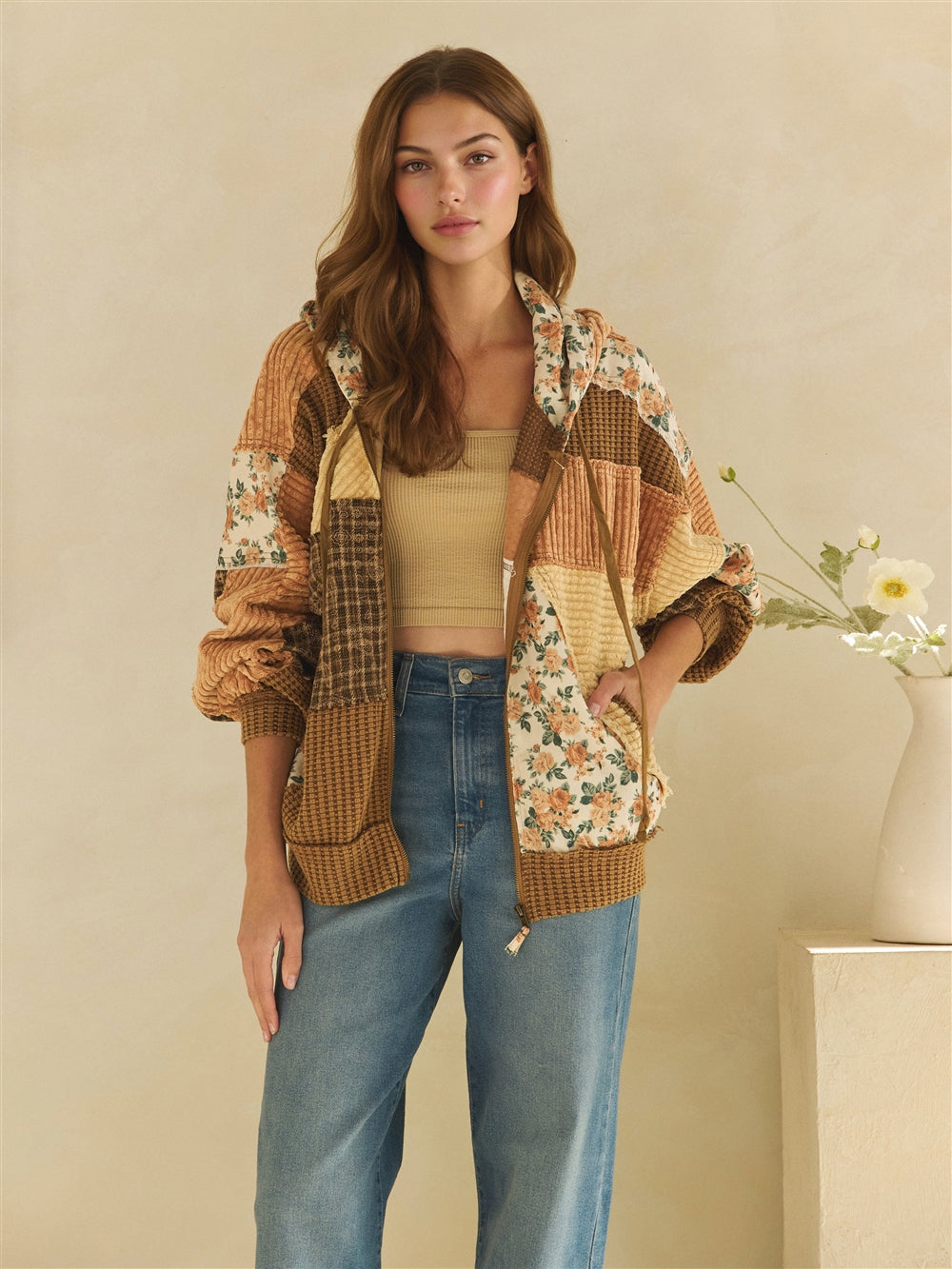 Back view of a brown hooded jacket with floral, plaid and textured patchwork panels.