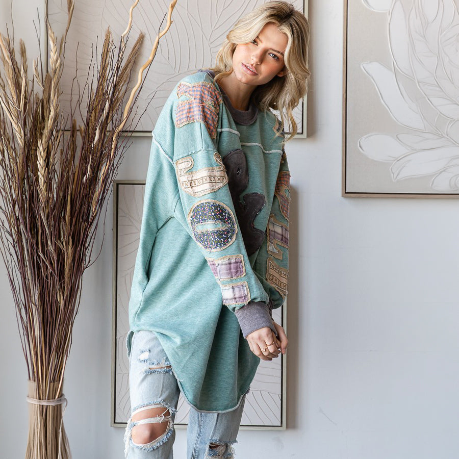 Oli & Hali sage patchwork pullover top, leaning pose showing sleeve detail and longline hem
