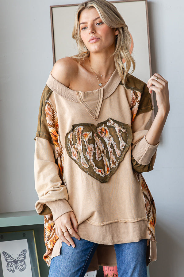 Front view of a tan heart patchwork pullover with olive shoulders, geometric side panels and ribbed cuffs