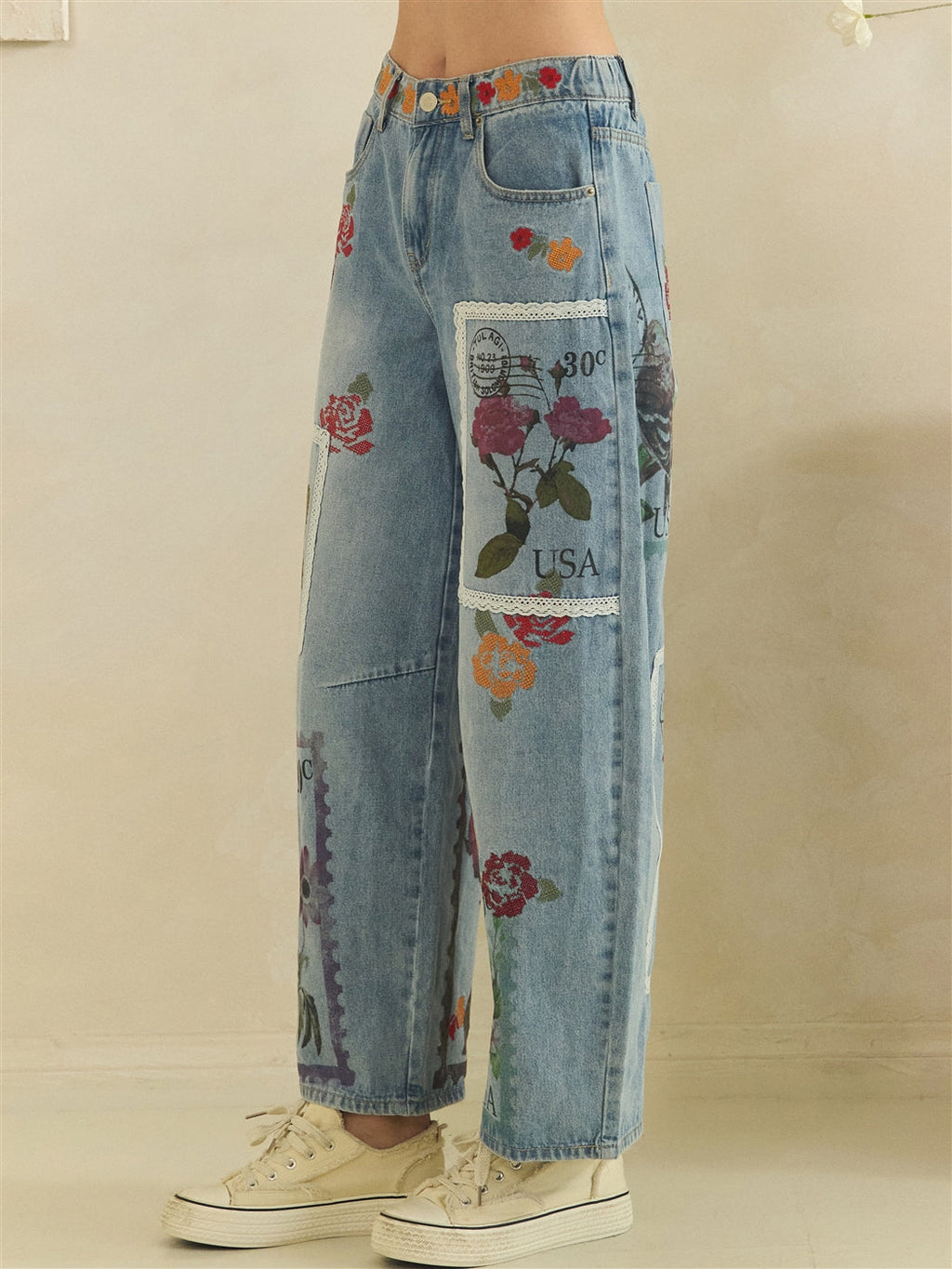 Side view of washed blue postage barrel jeans showing the rounded leg and floral panel details