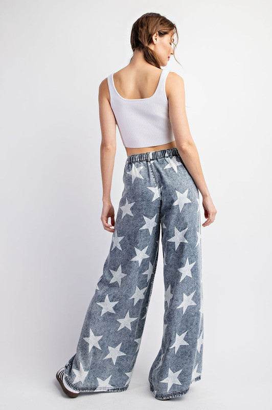 a woman wearing a white crop top and star patterned pants