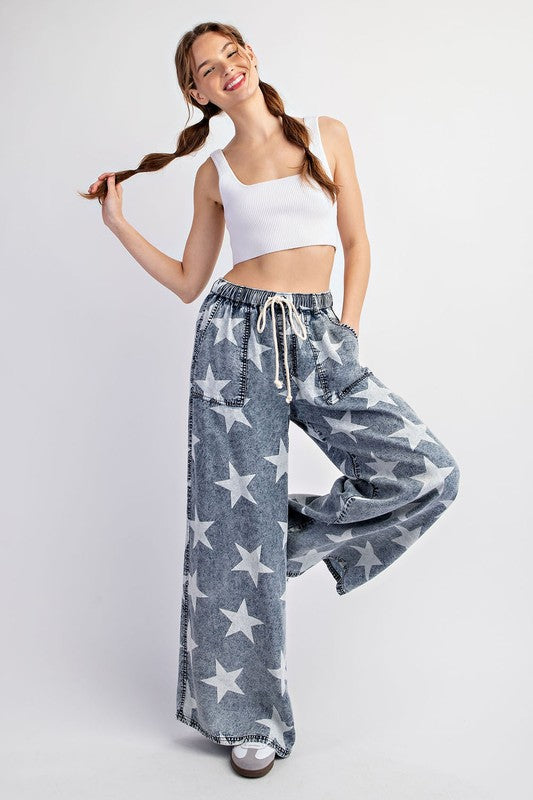 a woman in a white tank top and stars printed pants