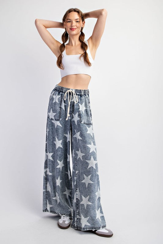 a woman in a white tank top and star print pants
