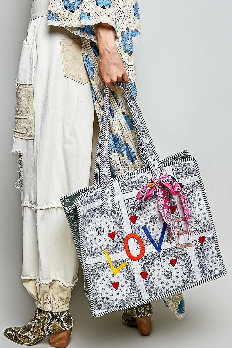 Paisley LOVE tote with pink bandana carried by a model, angled front view