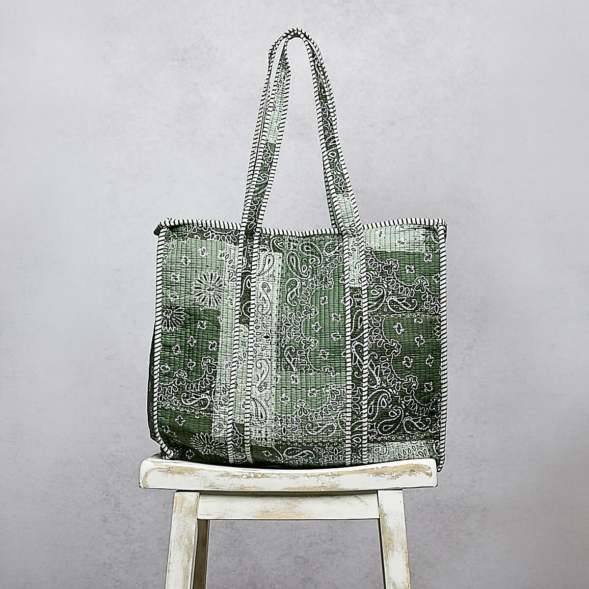 POL Clothing women's Green Multi paisley quilted tote displayed on a rustic stool