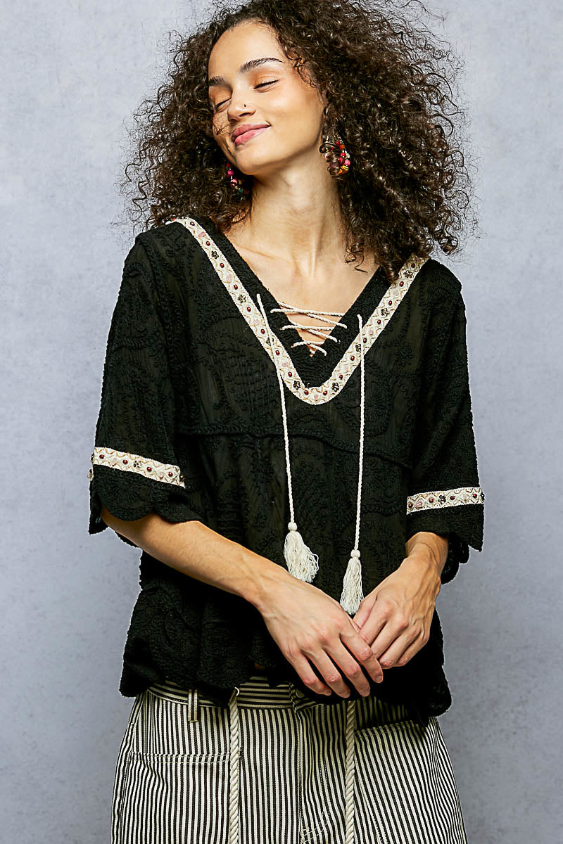 POL women's black crochet lace-up blouse on model, front close-up showing contrast trim and tassel ties
