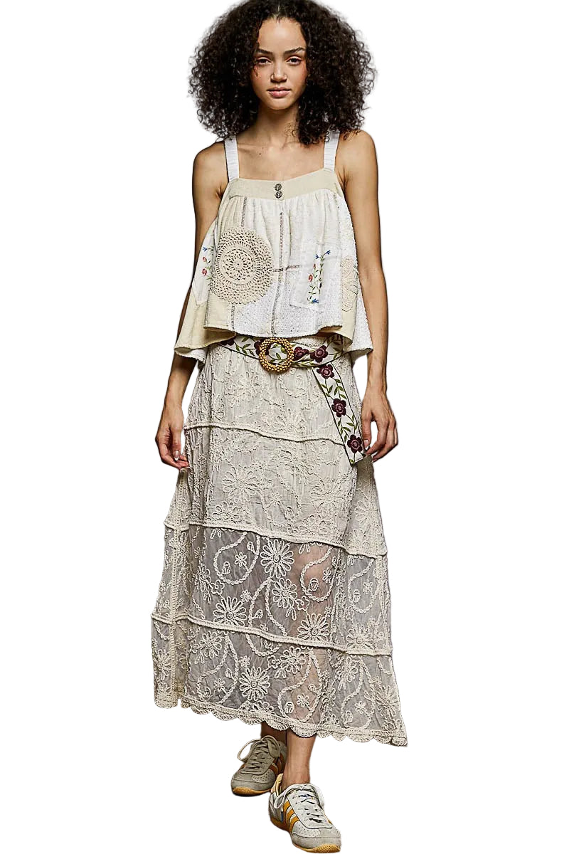 Woman wearing a layered dress with floral patterns against a plain background