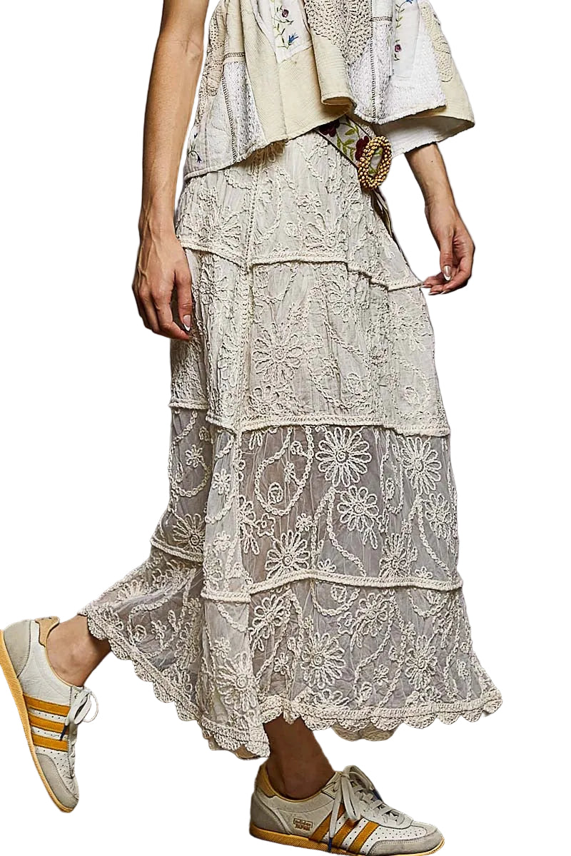 Person wearing a layered outfit with a lace skirt and Adidas sneakers on a textured floor.