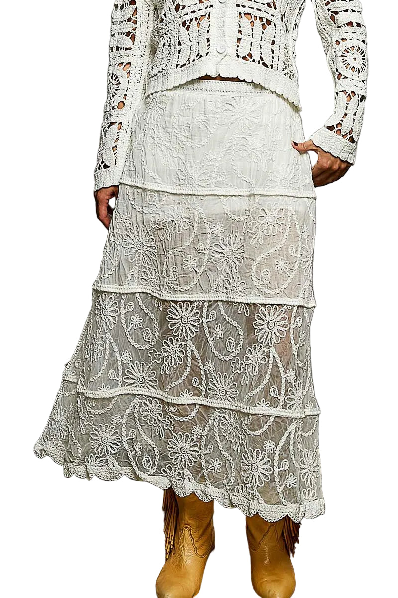 Person wearing a white lace outfit with boots on a textured floor.