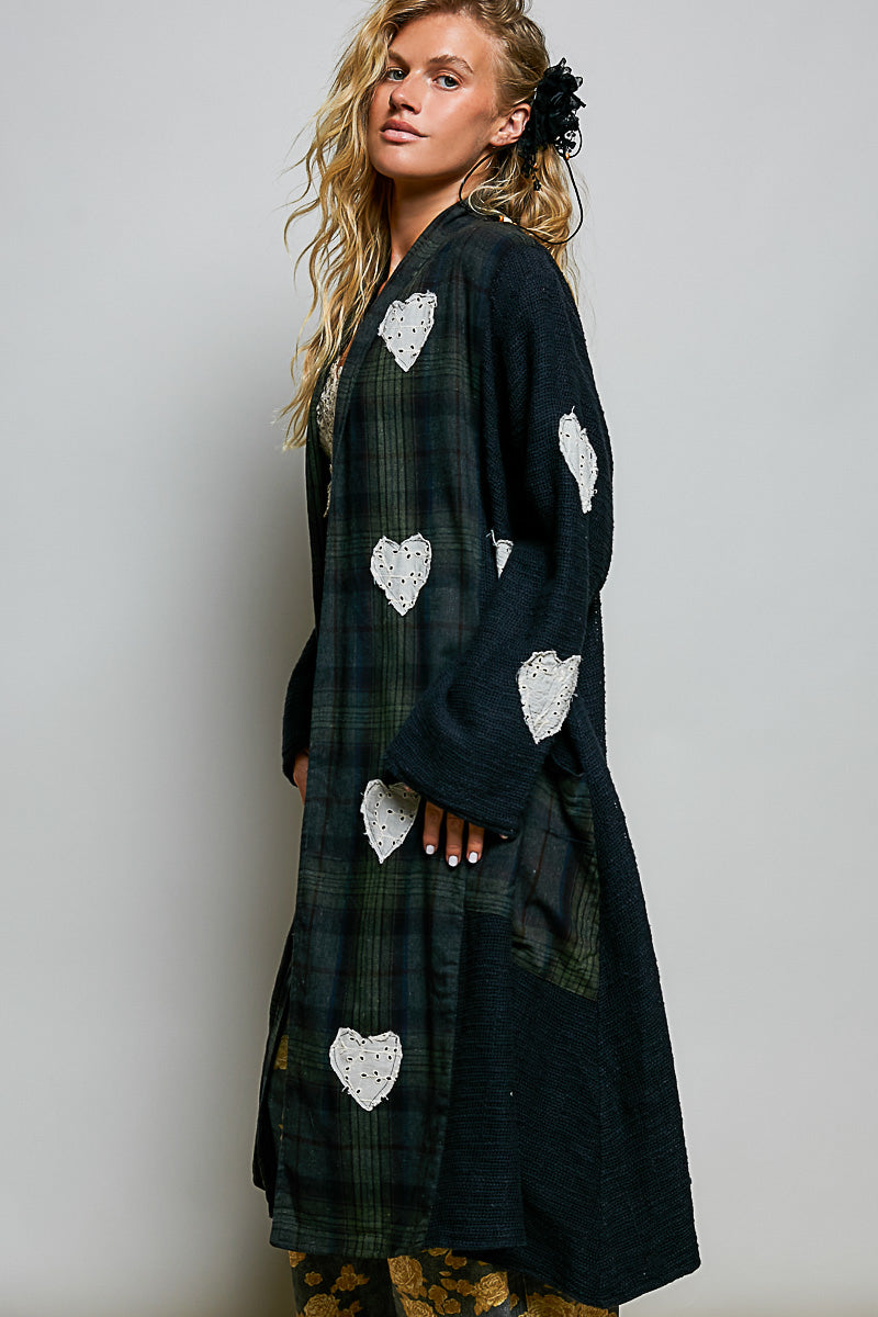 POL Clothing women's dark plaid longline coat with white eyelet lace heart appliqués, three-quarter side view on model
