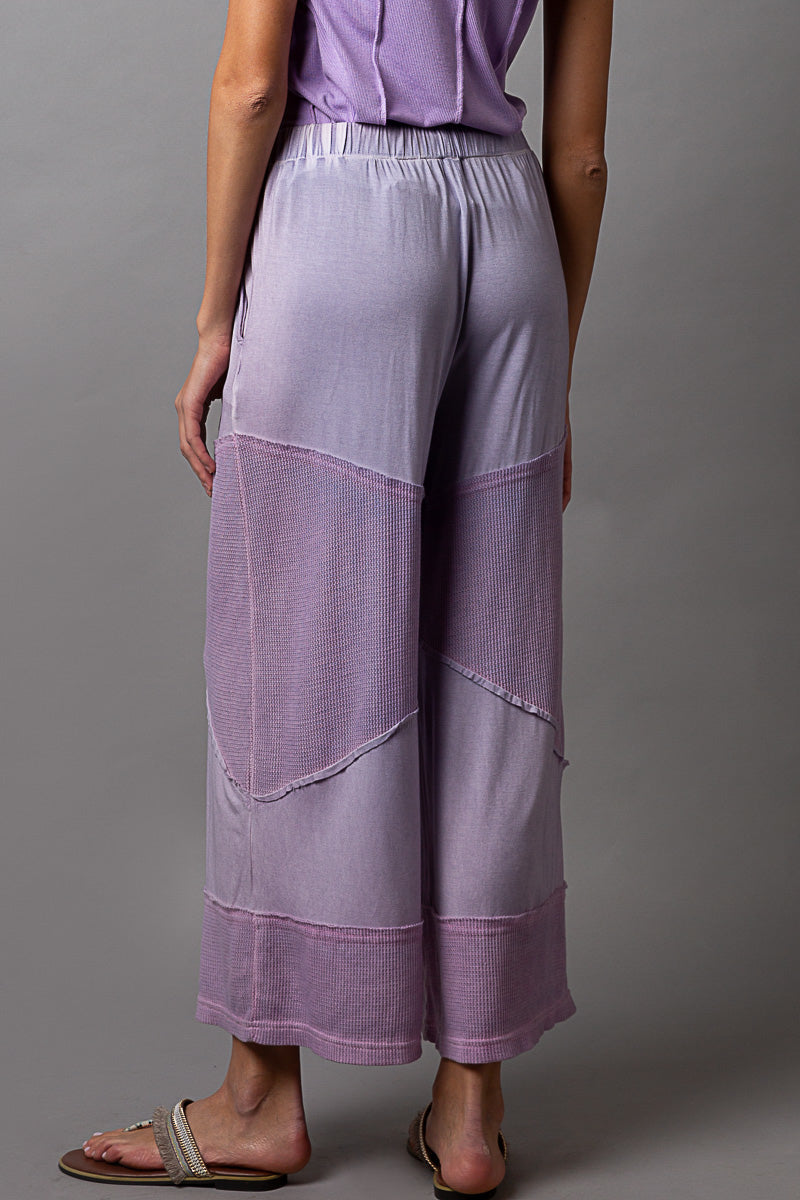 POL women's dusty lilac wide-leg culotte pants with colorblock panels and exposed seam detail, back view
