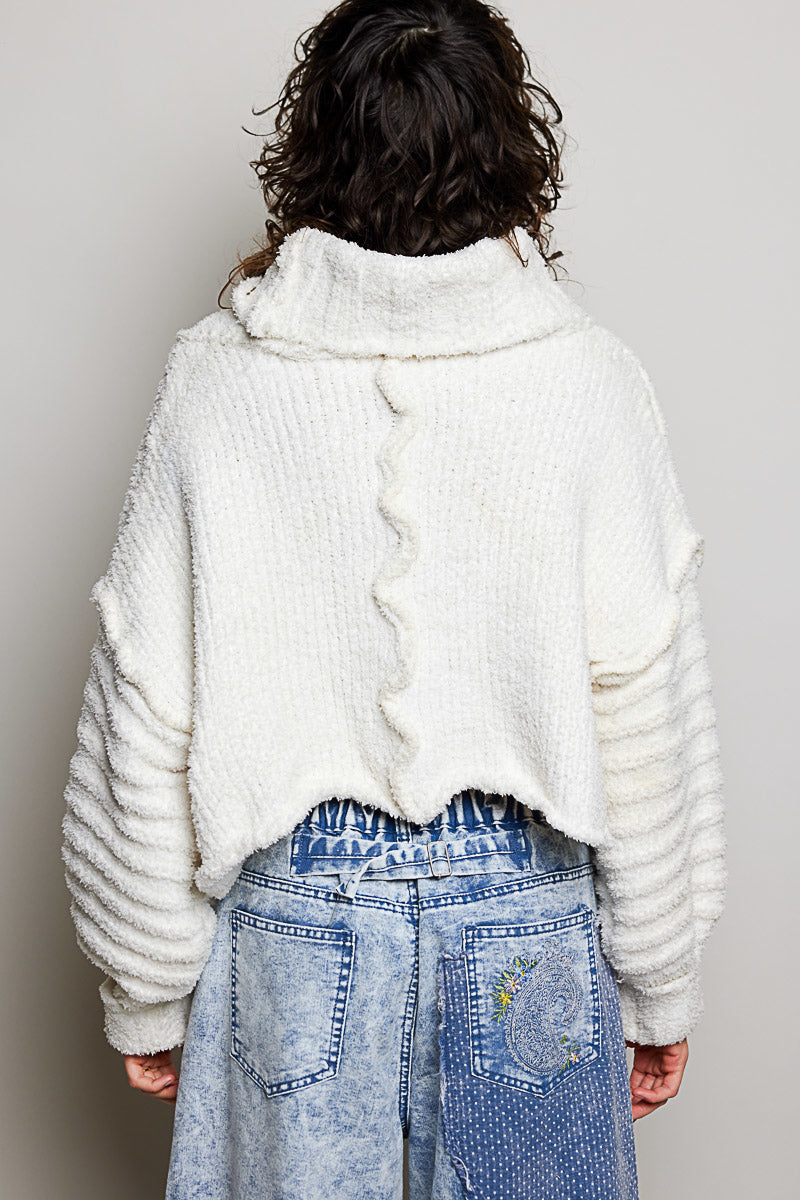 POL Clothing ivory boucle turtleneck sweater with pink floral patch, three-quarter front view on model
