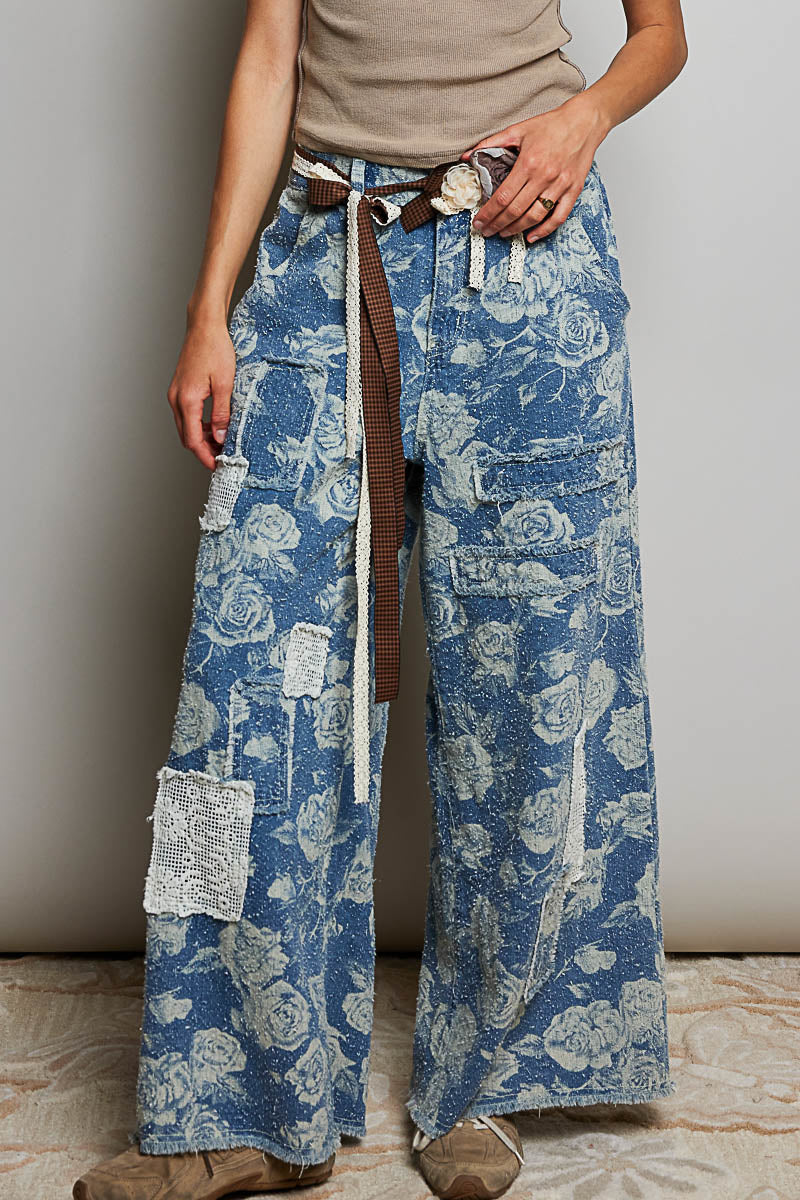 POL Clothing blue rose floral wide-leg denim pants, front detail view showing cargo pockets and crochet appliqués on model
