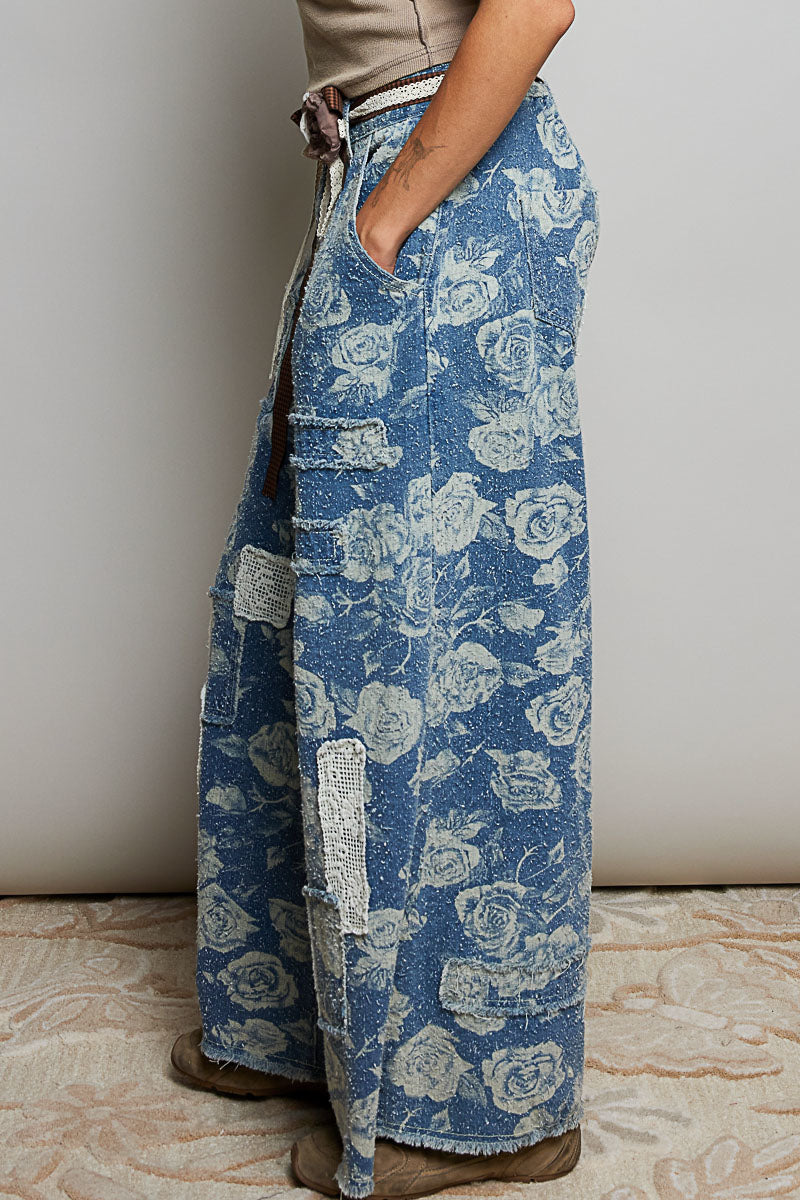 POL Clothing blue rose floral wide-leg denim pants, side view showing crochet patch detail and raw frayed hem on model
