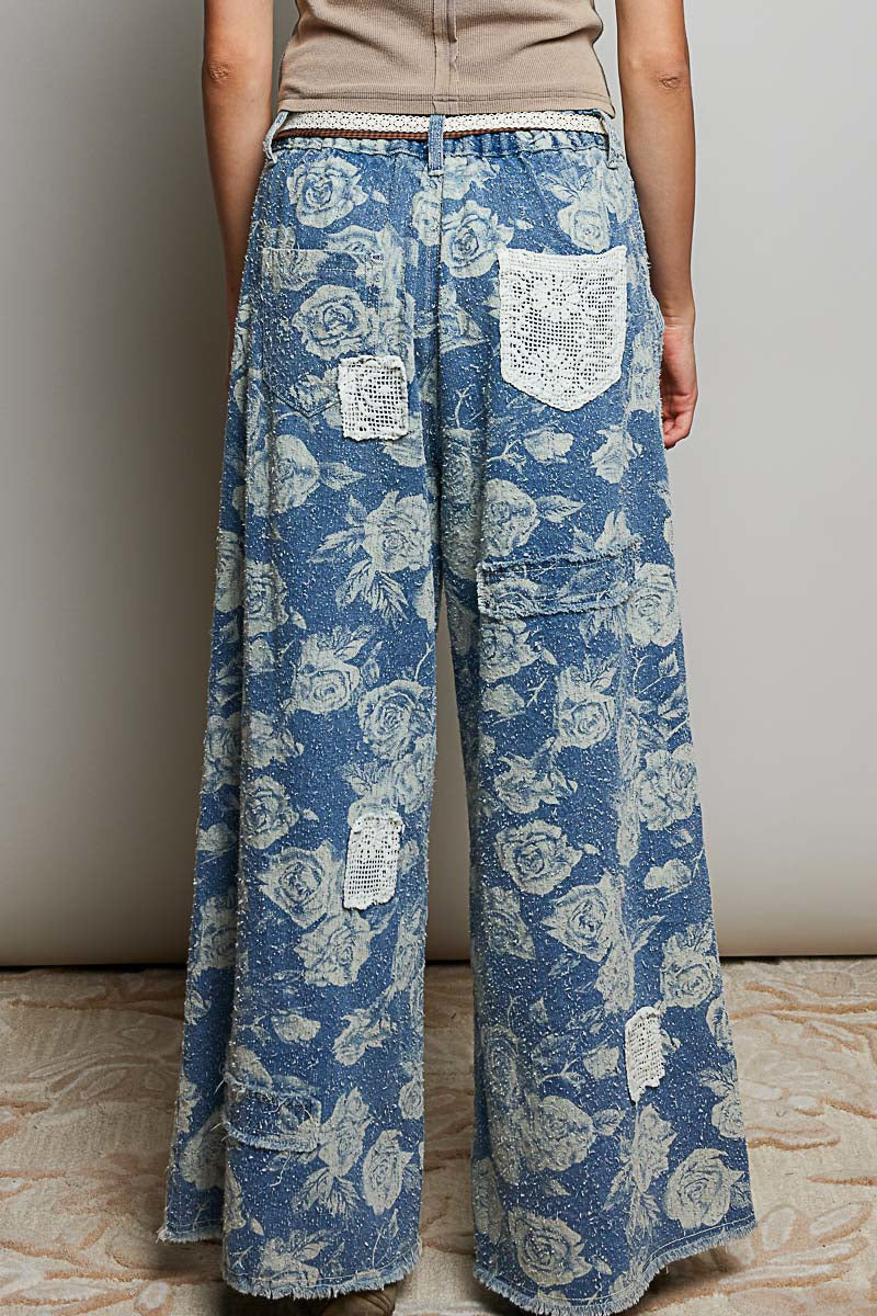 POL Clothing blue rose floral wide-leg denim pants, back view showing crochet pocket appliqués and wide-leg silhouette on model
