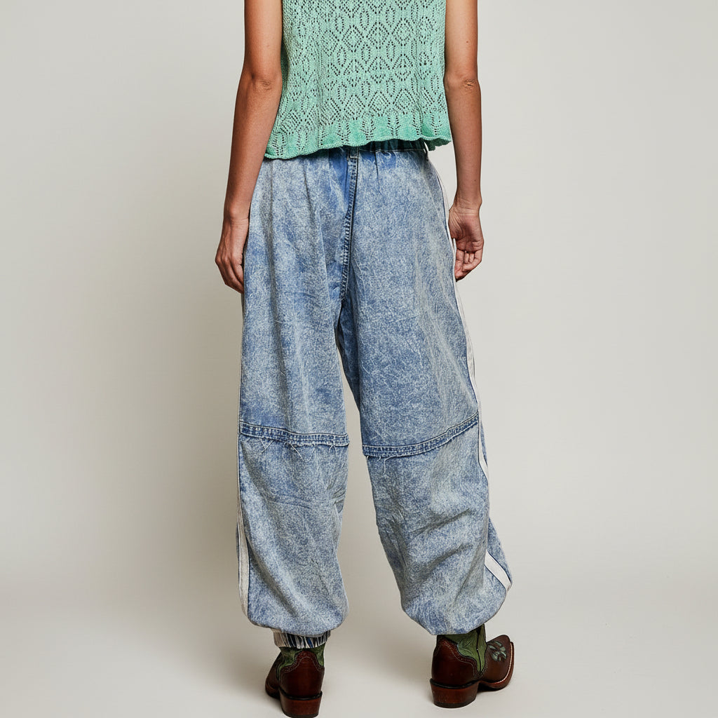 POL blue denim jogger pants, lower leg detail showing floral embroidery and elasticized cuff with western boots
