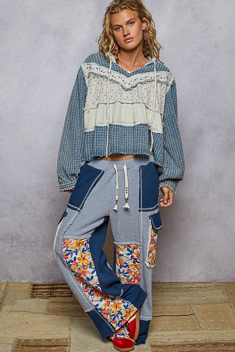 Front outfit view of a blue and cream floral hoodie styled with colorful patchwork pants.