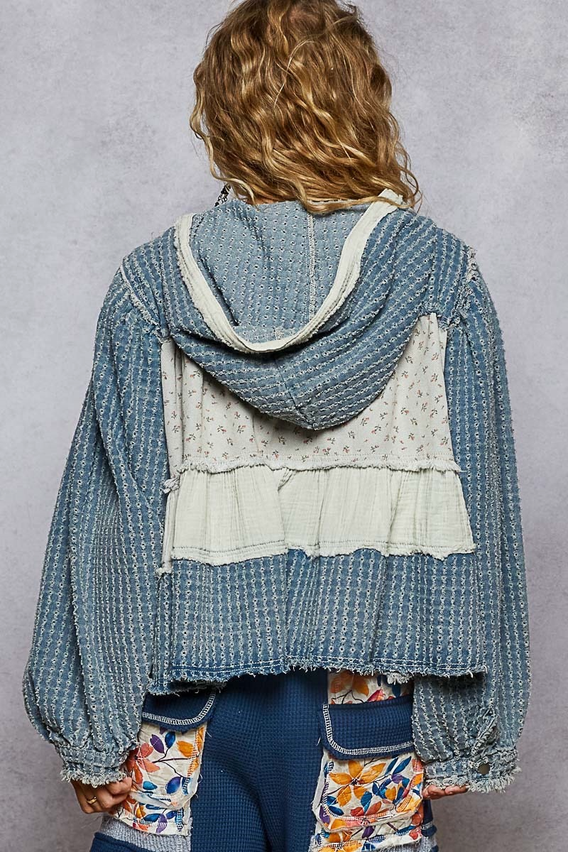 Back view of a blue textured hoodie with a cream-edged hood, floral patchwork and gathered fabric band.