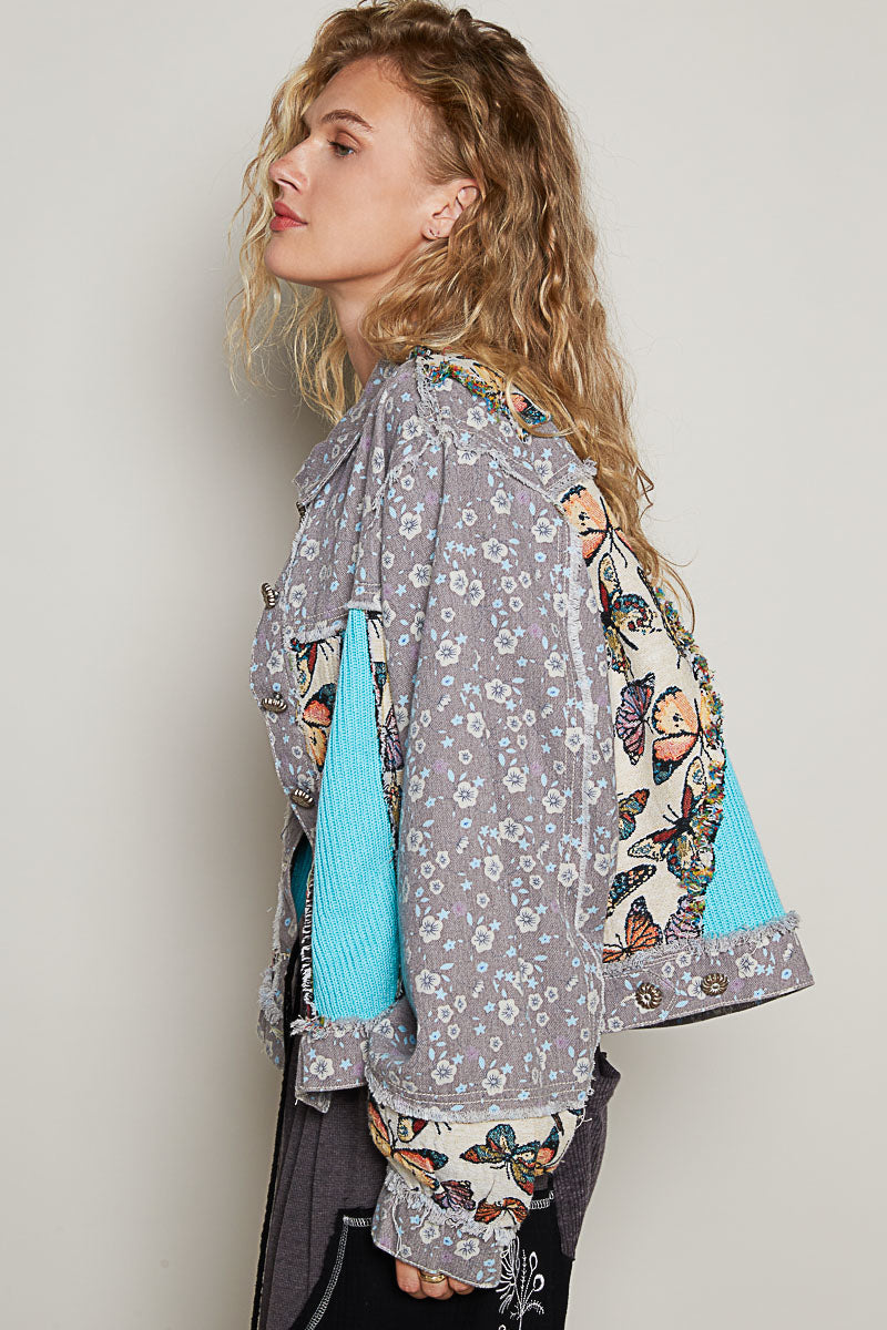 POL women's cropped denim jacket side view showing butterfly tapestry sleeve panel and turquoise ribbed knit insert detail
