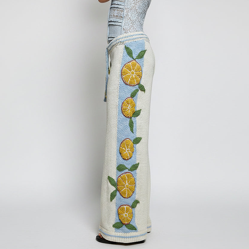 Side profile of POL Clothing citrus embroidered wide leg knit pants showing blue contrast side panel and striped cuff
