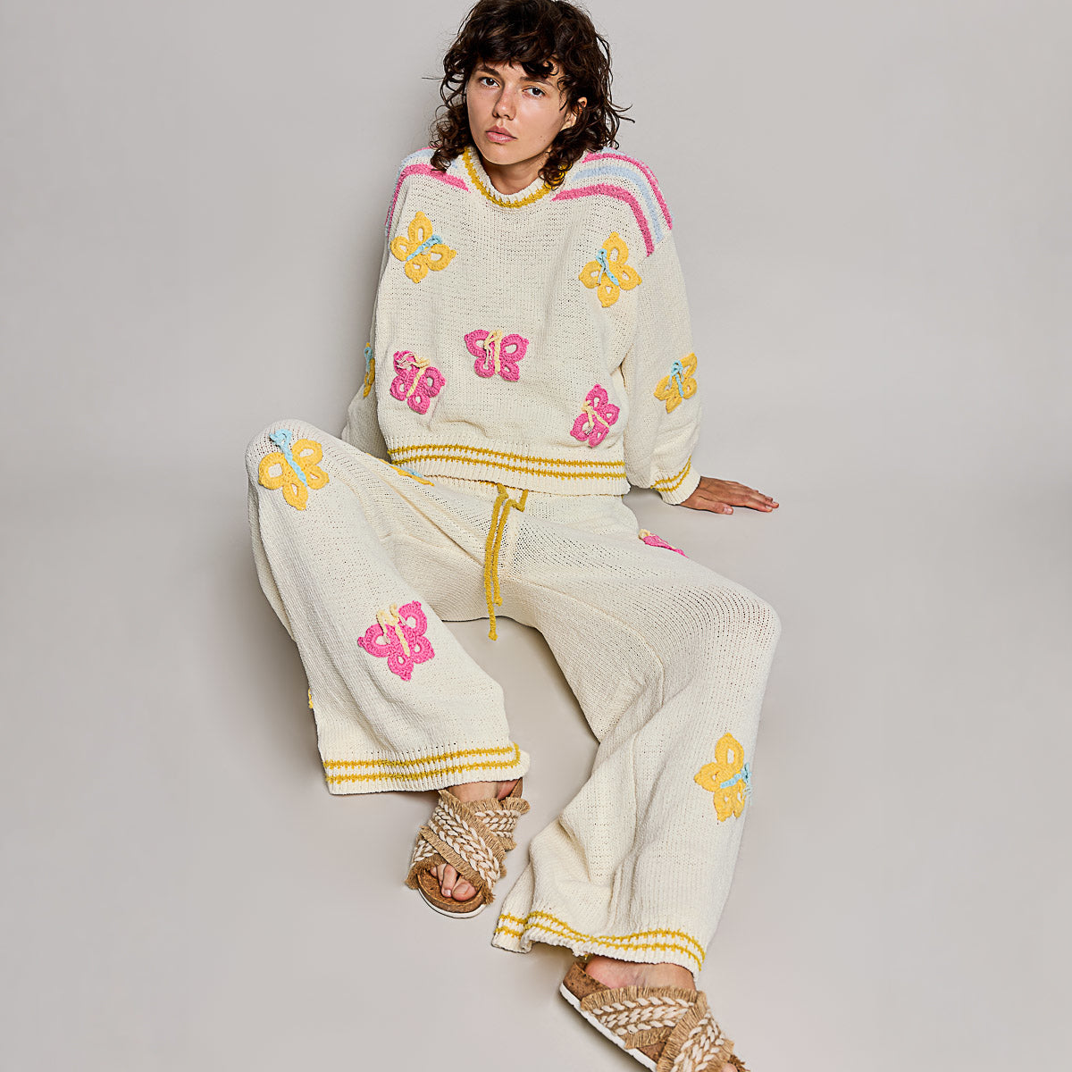 POL Clothing cream multi wide leg knit pants lower half, showing yellow stripe hem detail and butterfly appliques
