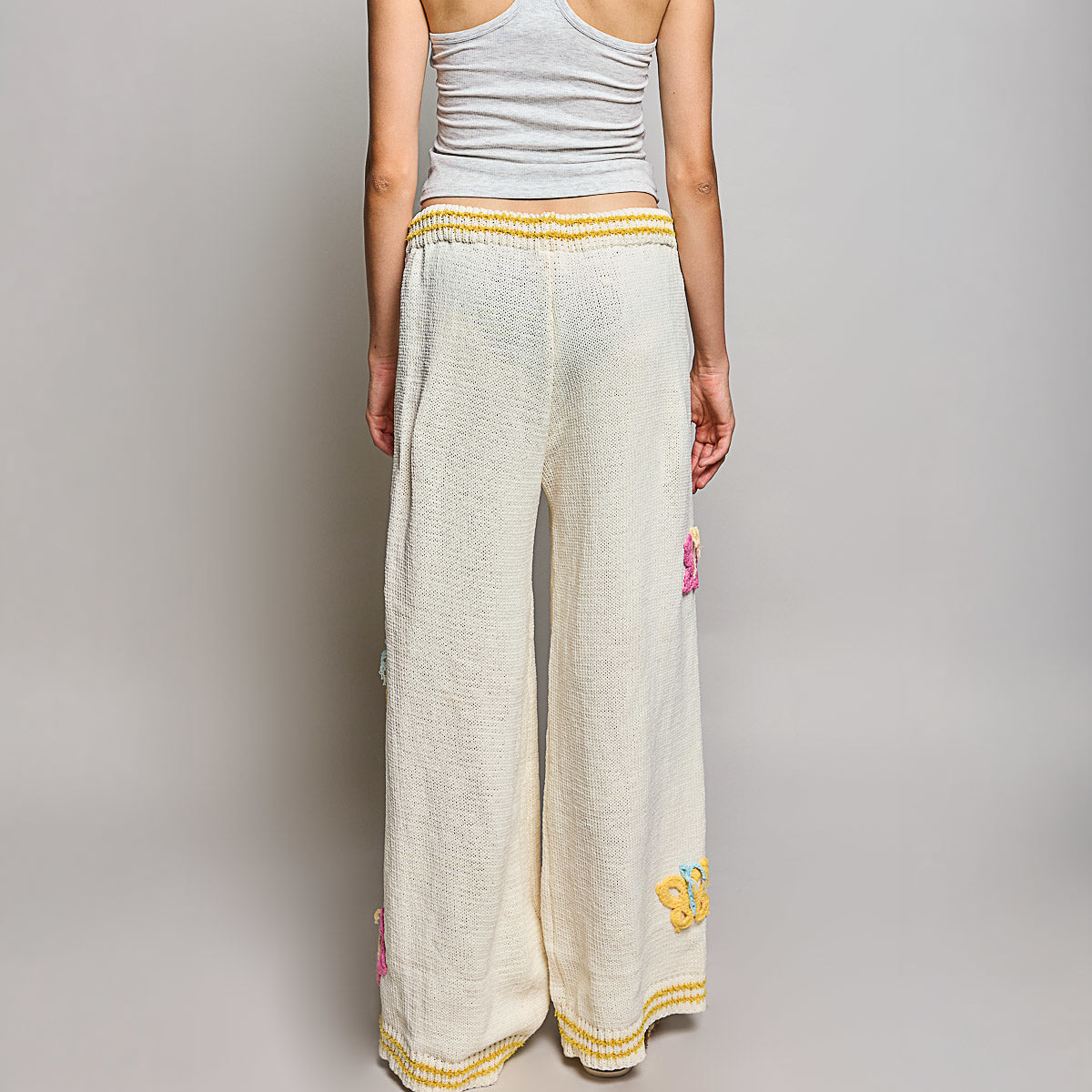 POL Clothing cream multi wide leg knit pants full-length back view on model showing knit fabric and butterfly appliques
