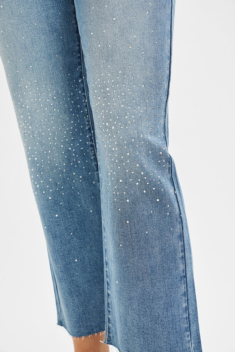 Close-up of blue jeans with rhinestone embellishments on a white background