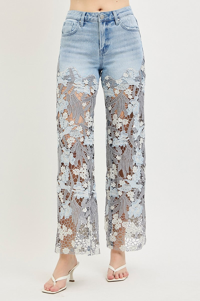 Light blue jeans with floral lace overlay on a plain background