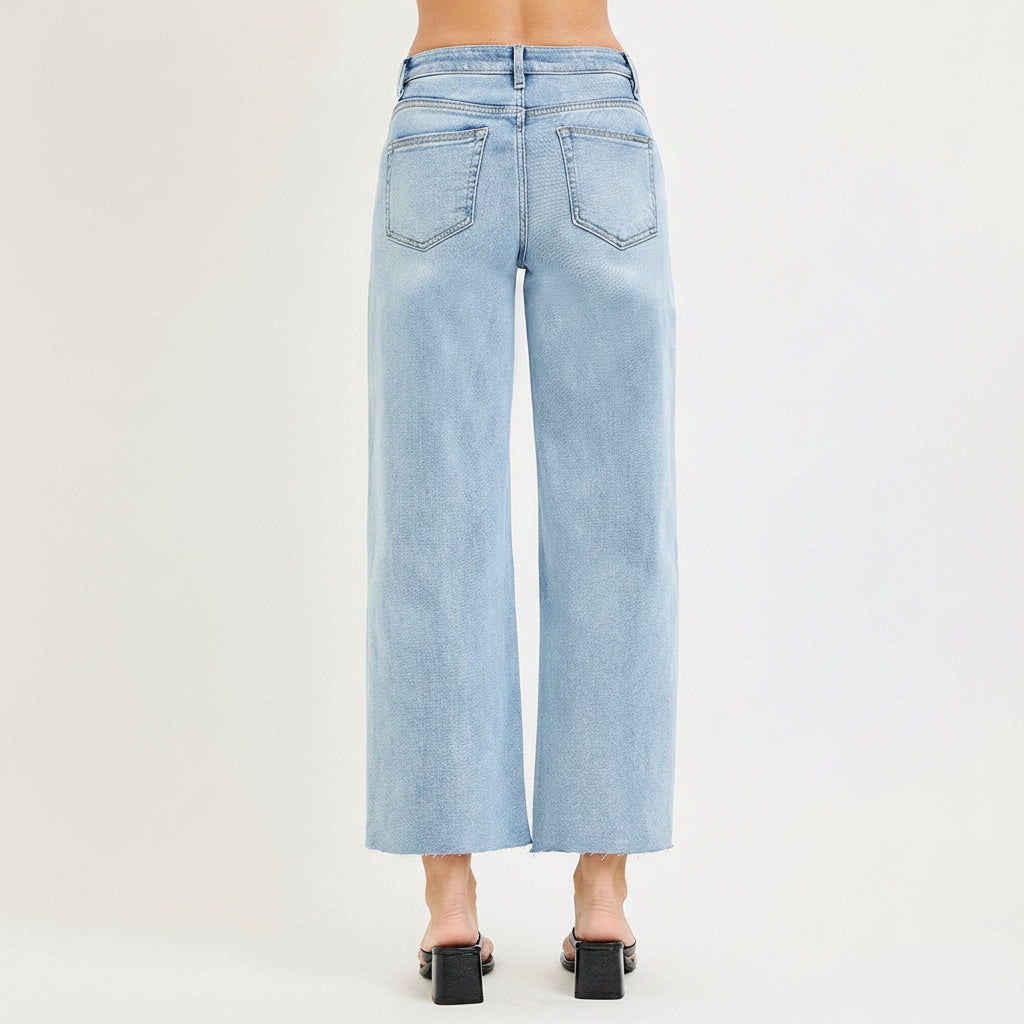 Straight front view of Risen light blue crop wide leg jeans with white floral lace side insets