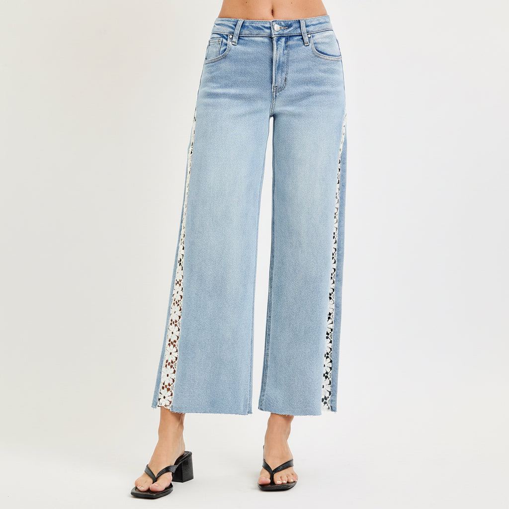 Close-up of Risen light blue jeans showing front pocket, washed denim texture, and white floral lace inset