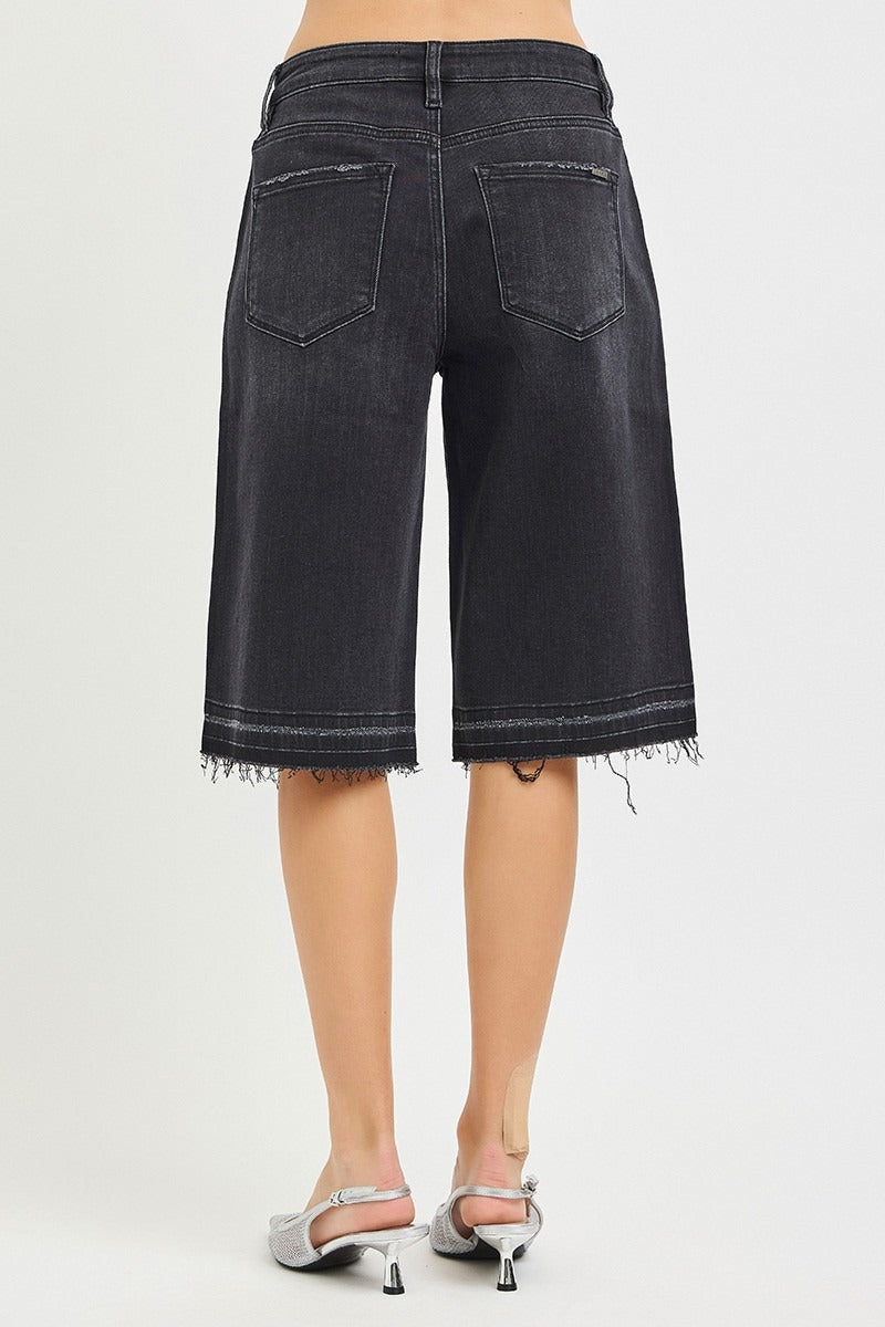 Black denim shorts worn by a person on a white background