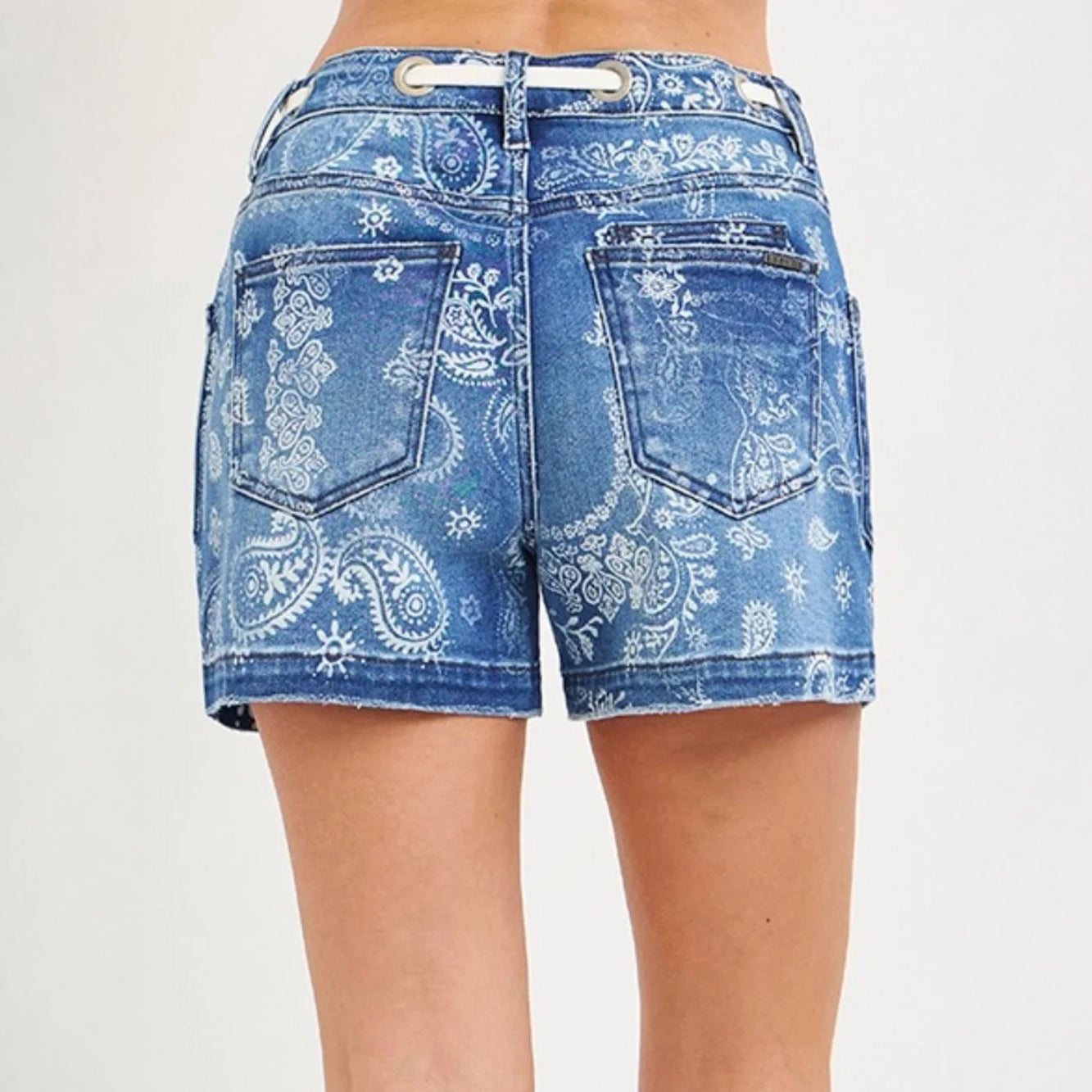 Rear view of a person wearing blue denim shorts with a white paisley bandana print, shown against a plain light background.