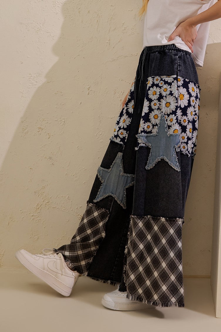 Sage + Fig denim patchwork pants close-up showing drawstring waist, star appliqués and plaid hems