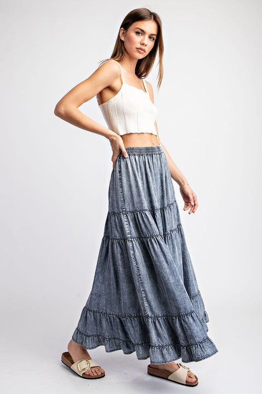 a woman wearing a white crop top and a blue tiered skirt