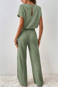 a woman wearing a green jumpsuit and white sneakers