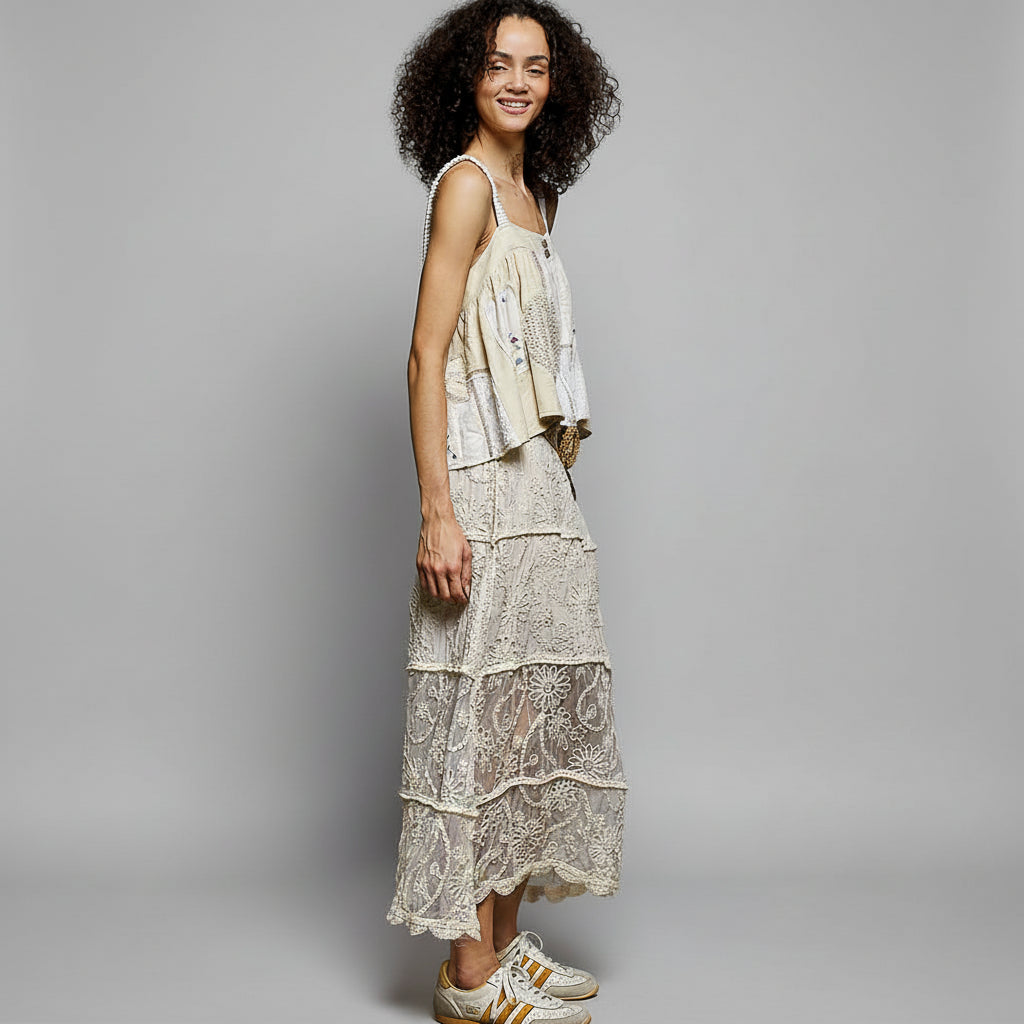 Woman wearing a layered dress with lace details against a textured wall.